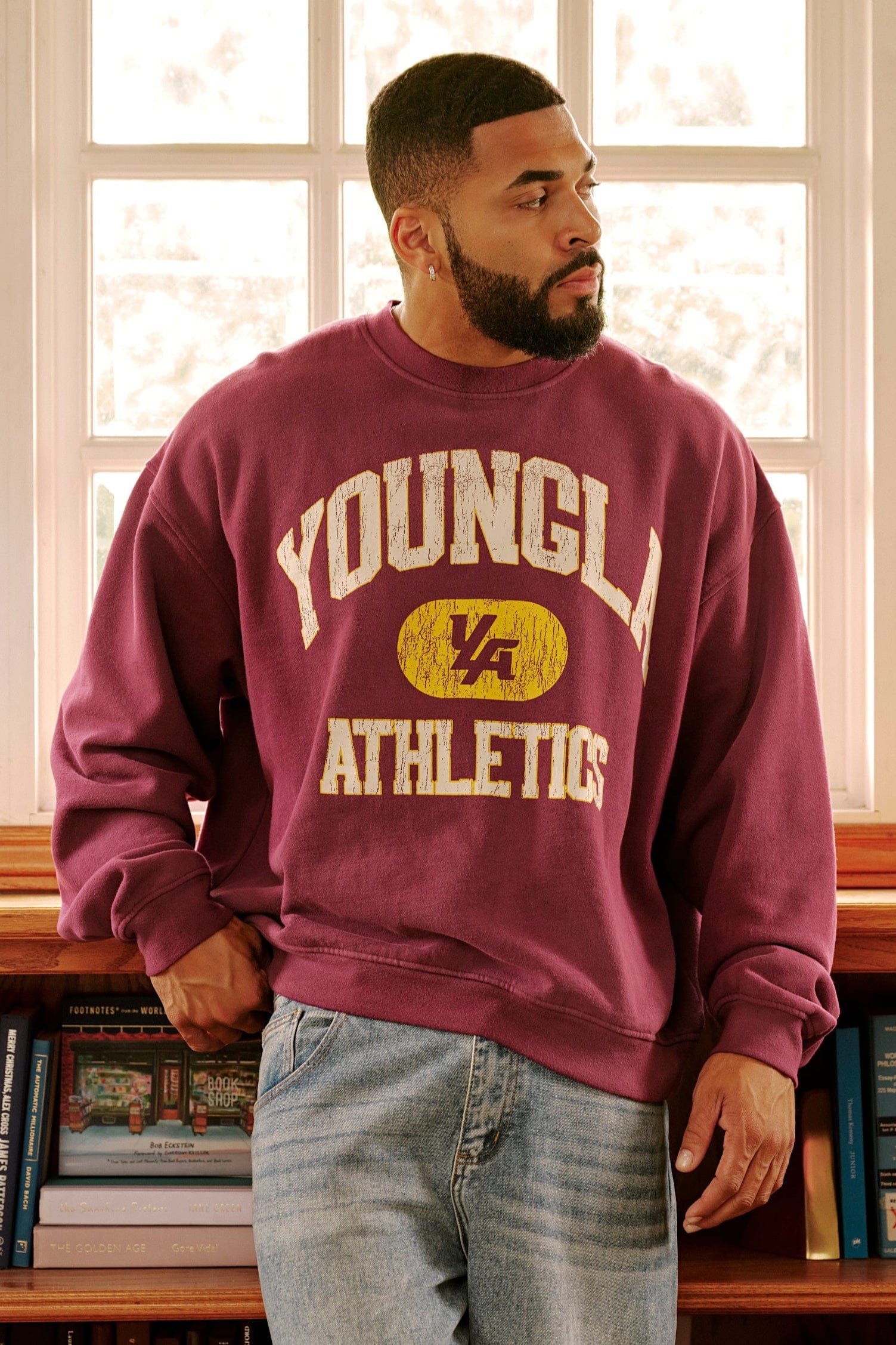 Front angle of model wearing oversized black crewneck with varsity print in urban setting