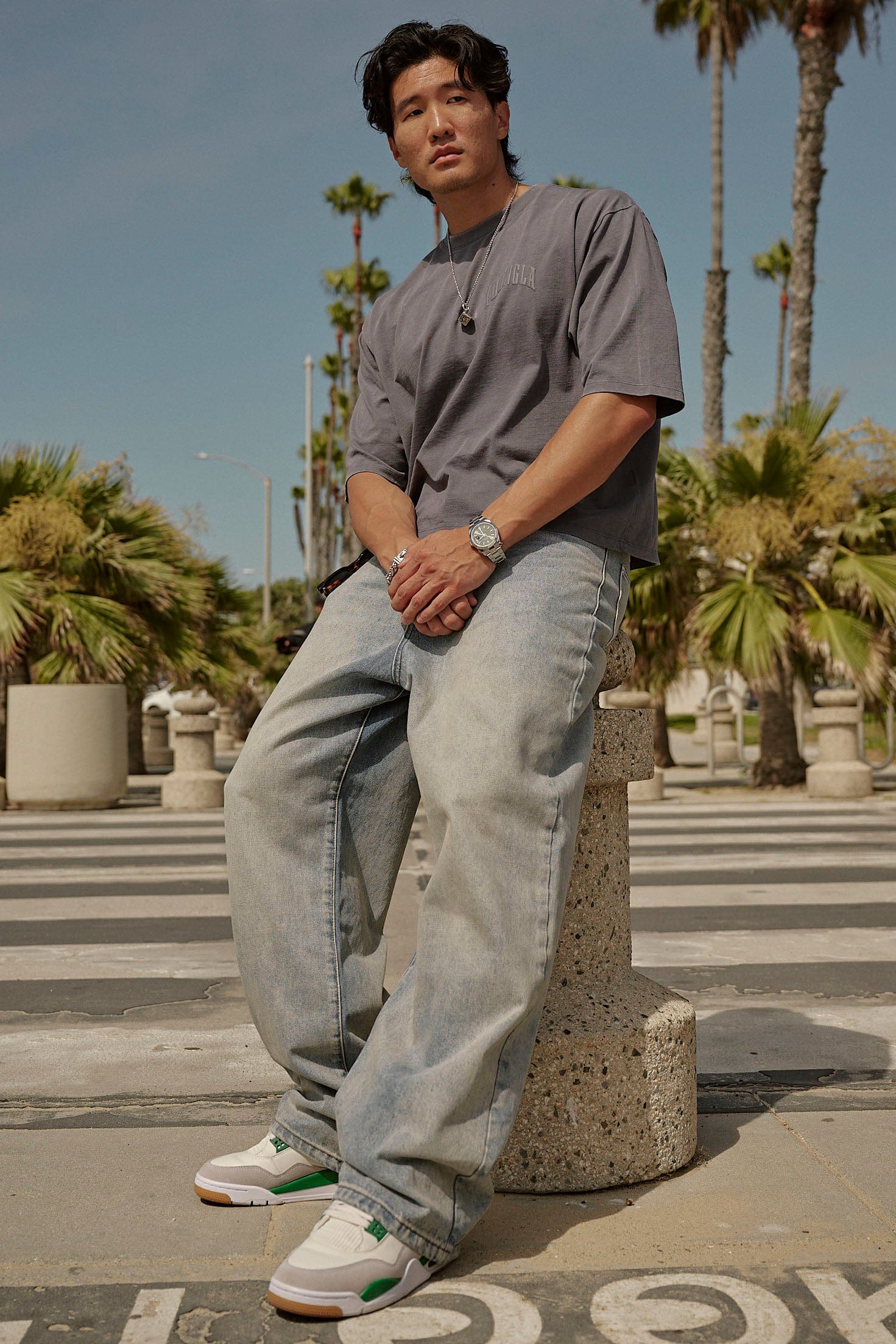 Front view of low rise baggy jeans styled with high-top sneakers on city sidewalk