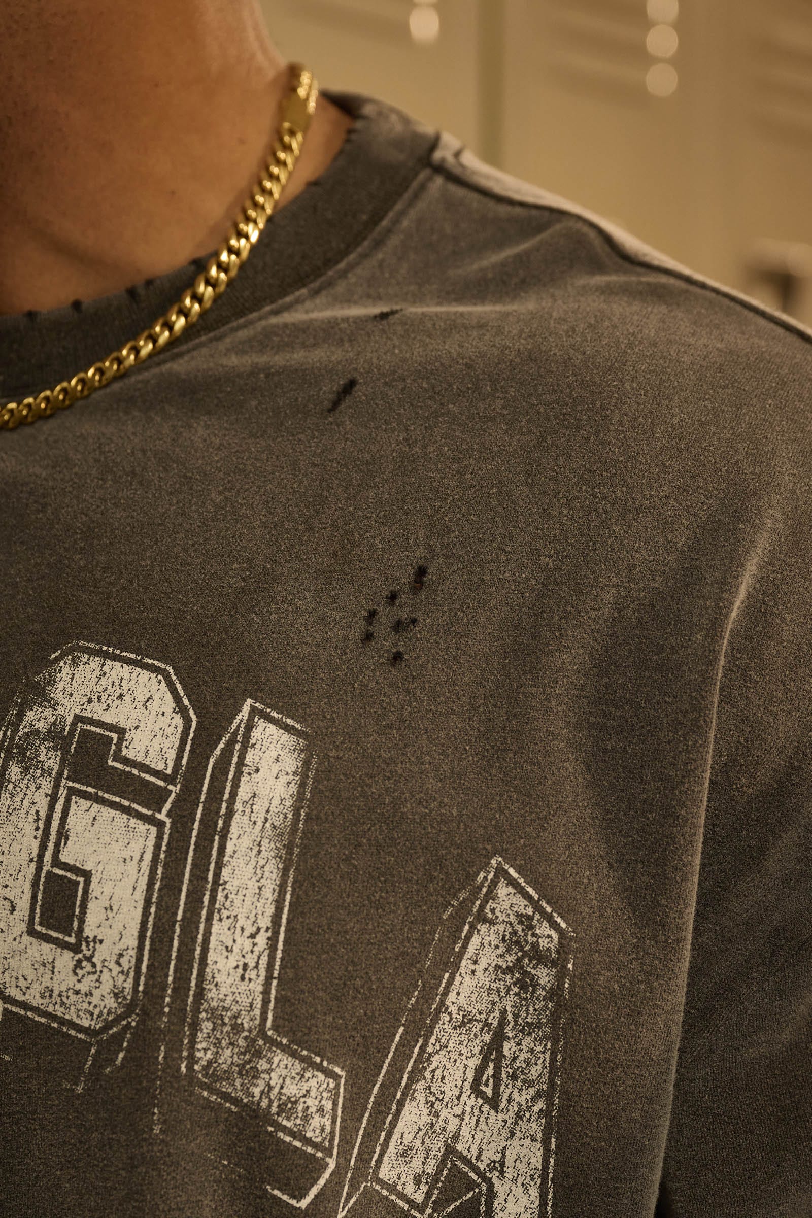 Close-up of vintage t shirt’s distressed cuts and arched logo