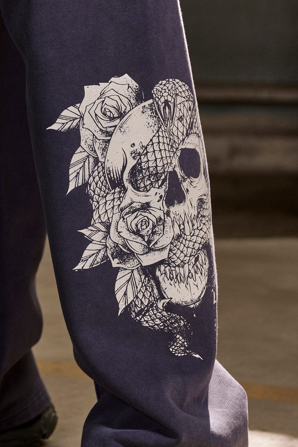 Side view of graphic sweatpants showcasing skull and floral designs.