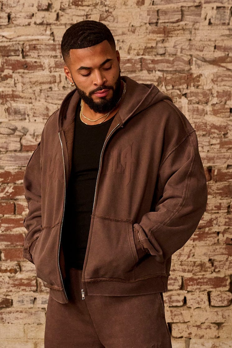 Front angle of black zip up hoodie styled with relaxed jeans.