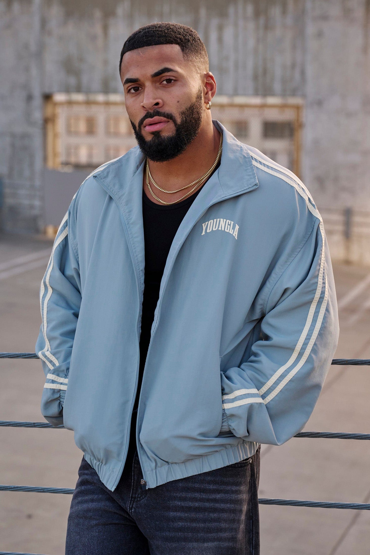 Side view of the black zip-up jacket, highlighting the sleeve stripes.