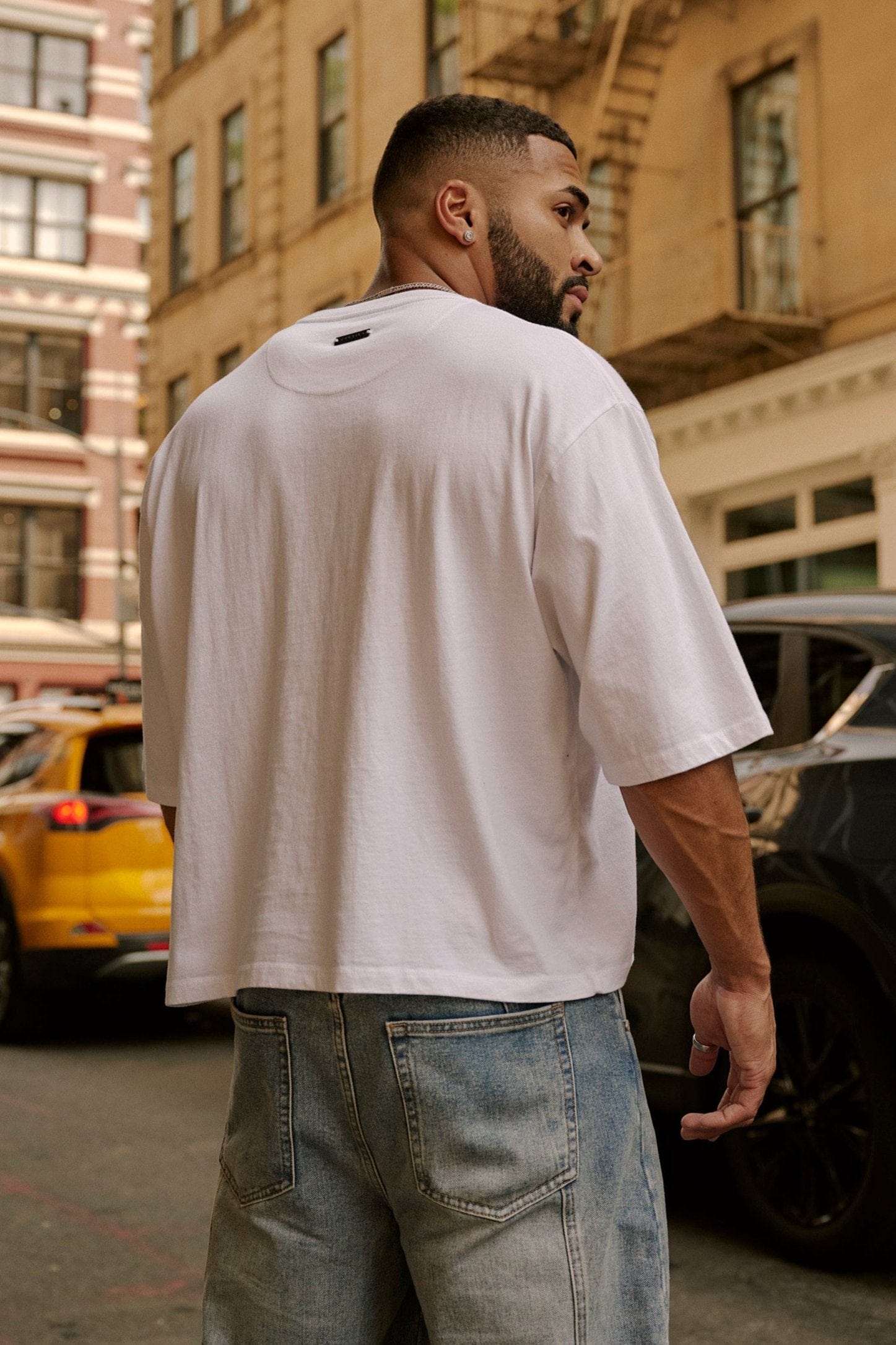 Model wearing loose fit cotton t-shirt with cropped length and minimalist logo