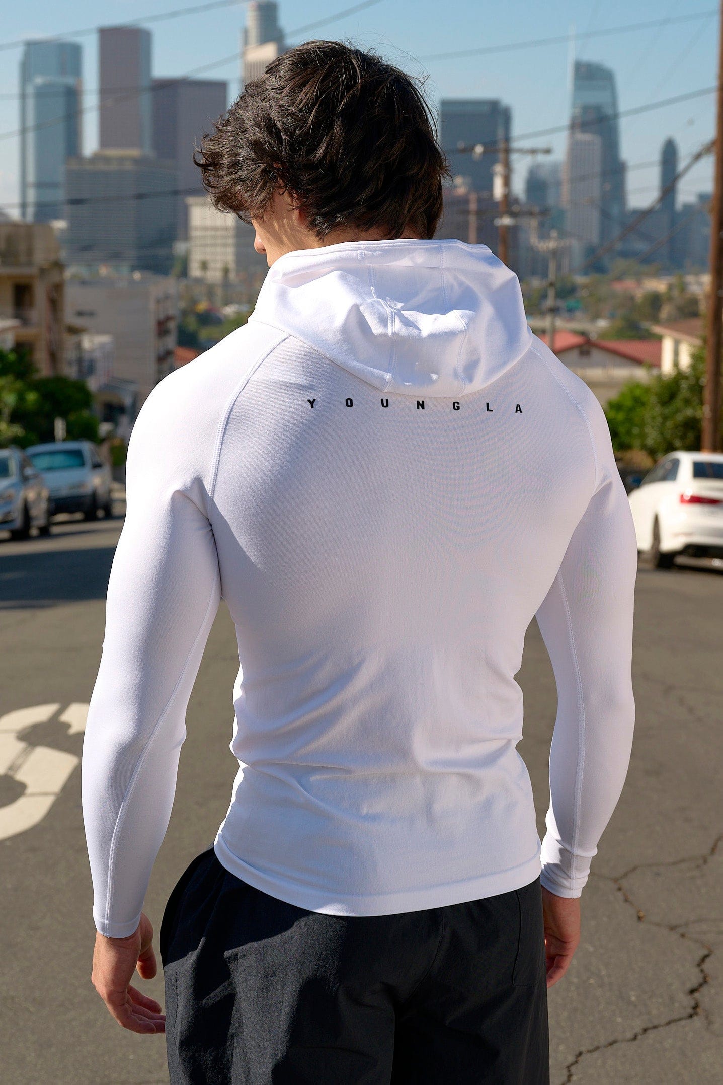 Side angle of compression hoodie emphasizing fit and fabric texture in gym lighting.
