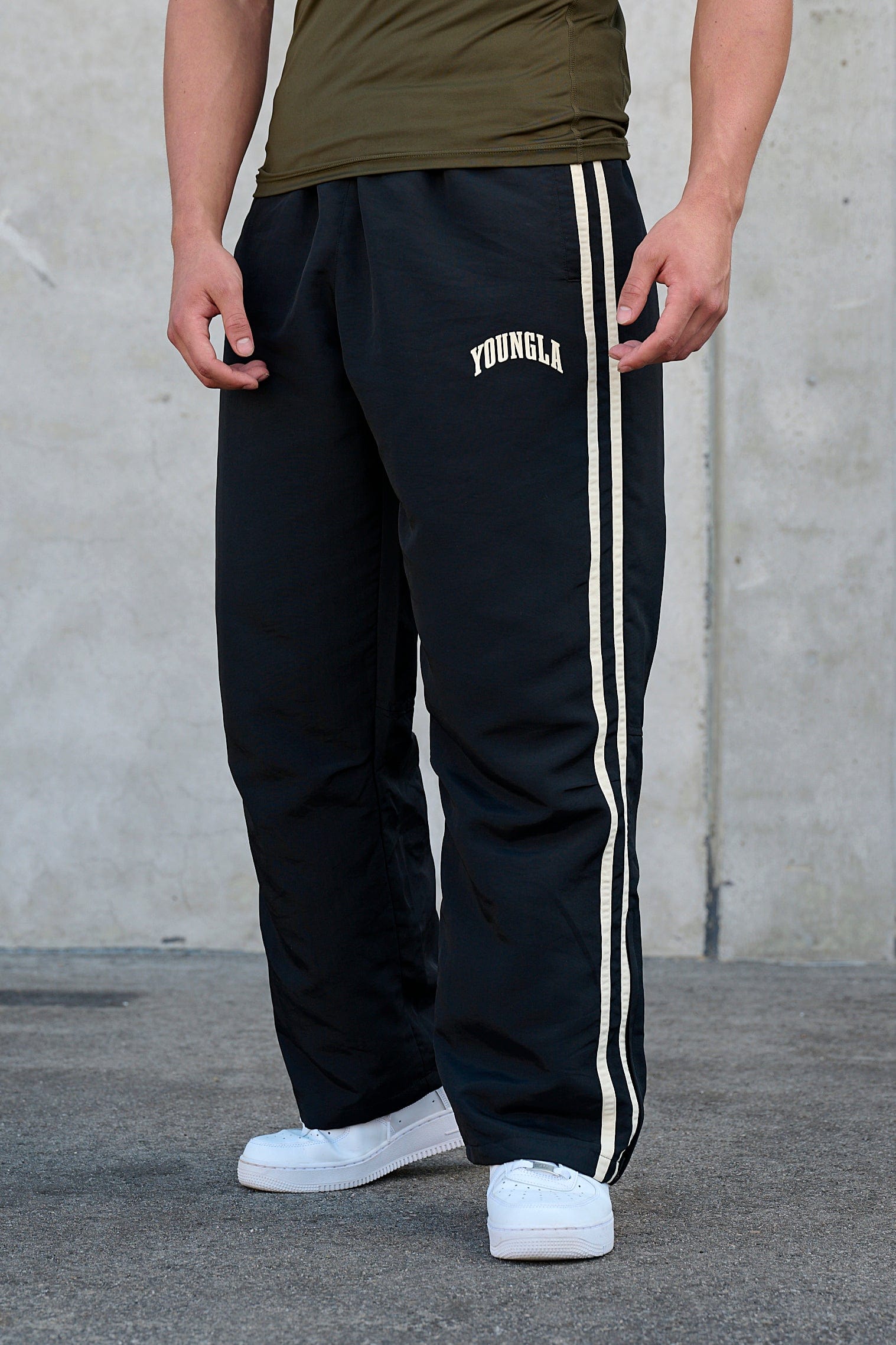 Front view of vintage-inspired track pants showcasing loose fit and side strips.