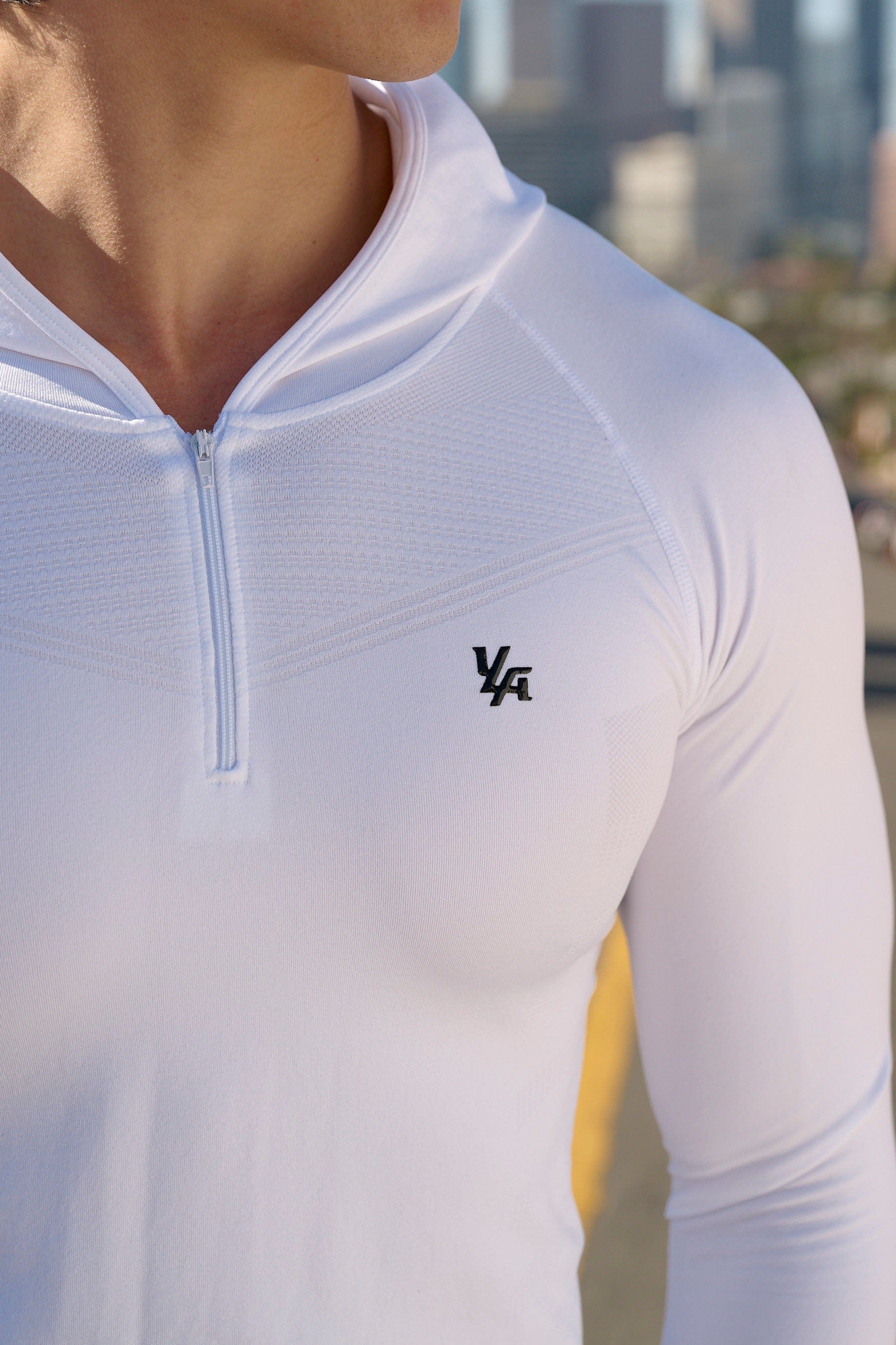 Side angle of compression hoodie emphasizing fit and fabric texture in gym lighting.