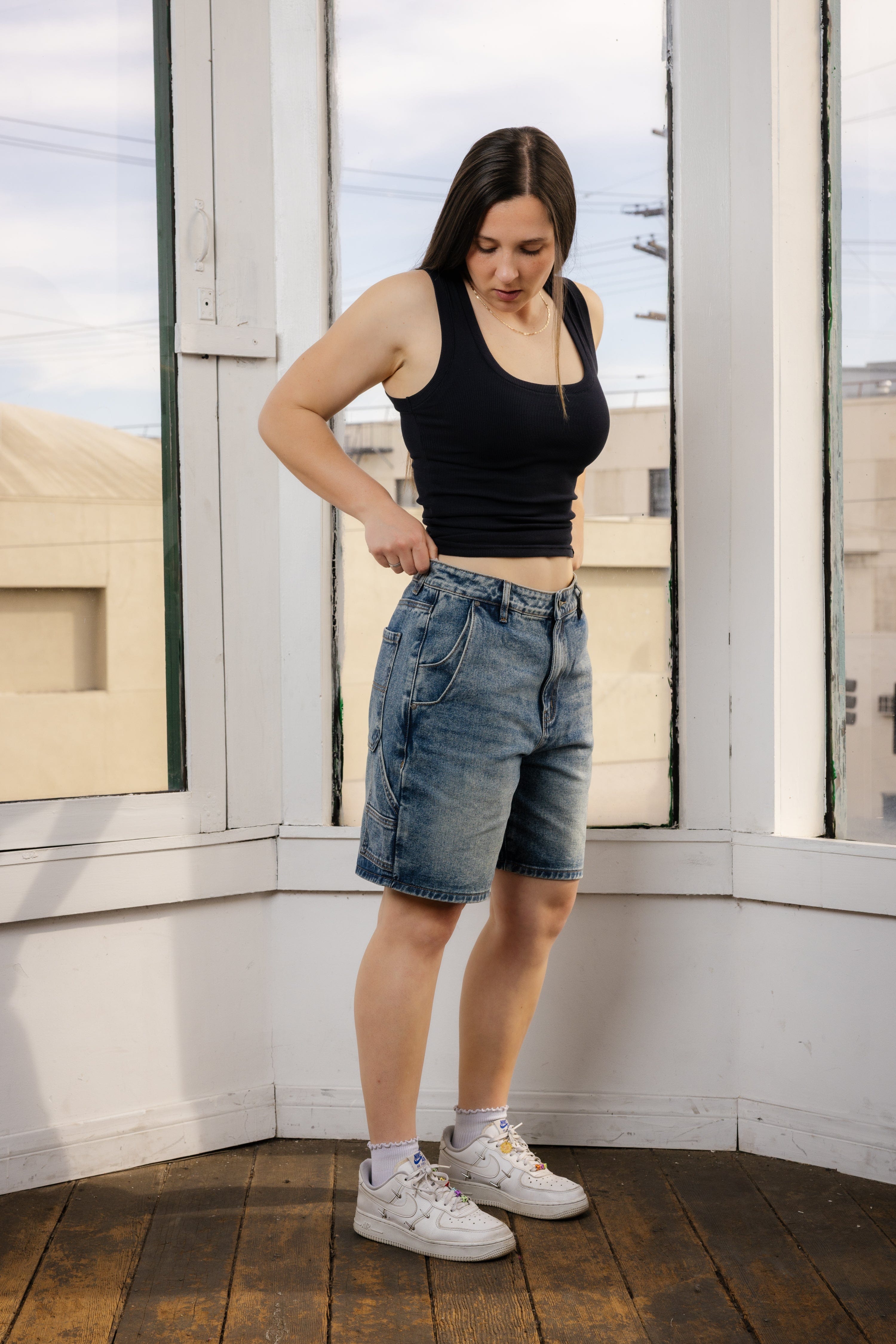 Laid flat light blue denim jean shorts mens on rustic wood surface showcasing relaxed cut.