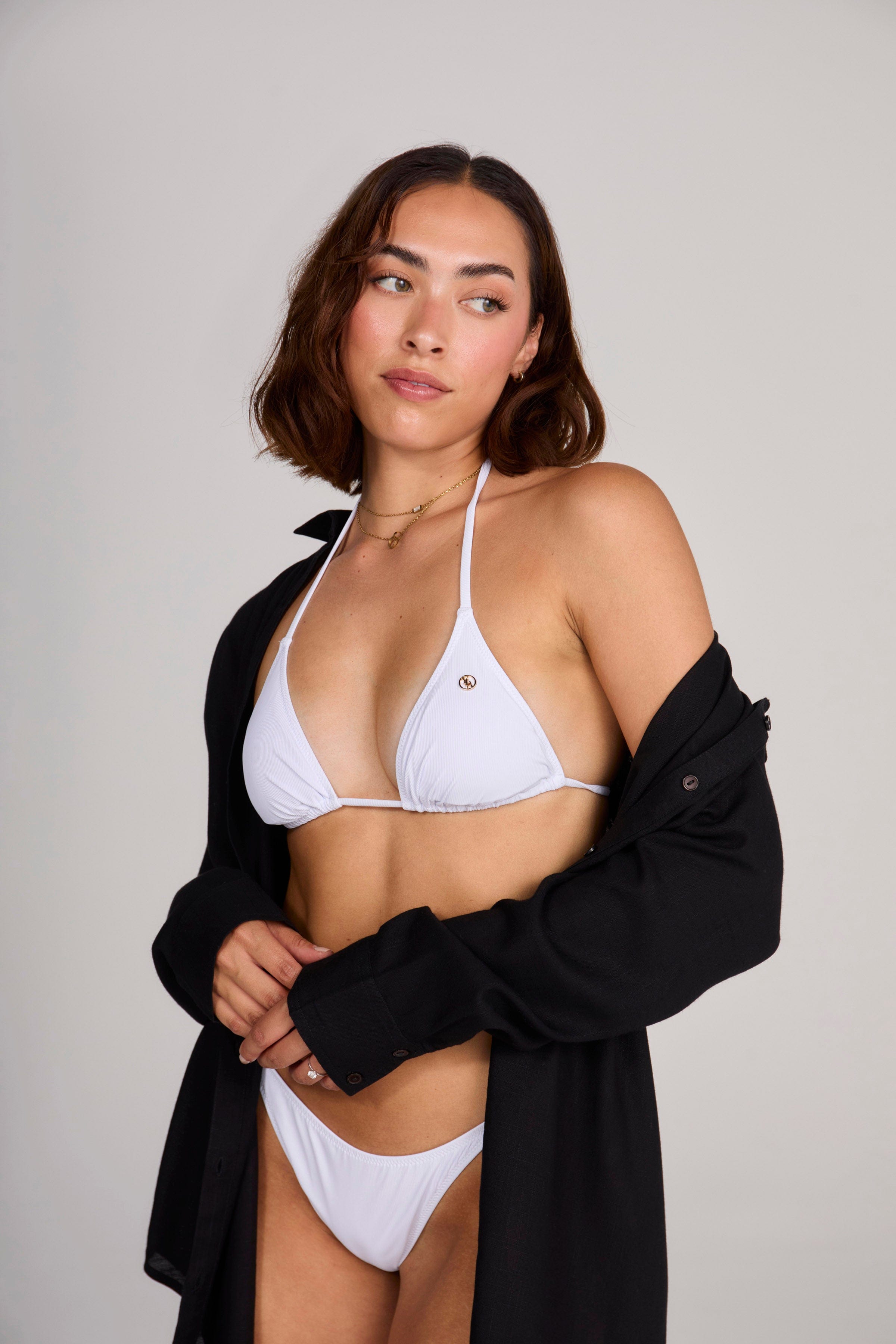 Model wearing a white beach cover up at the beach.