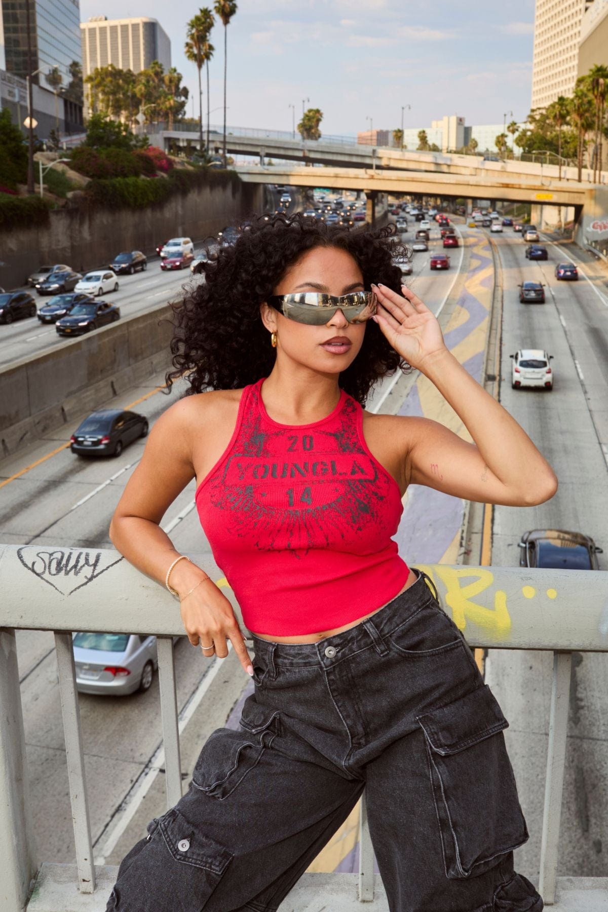 Model wearing a graphic tank top paired with cargo jeans, embodying modern streetwear style.