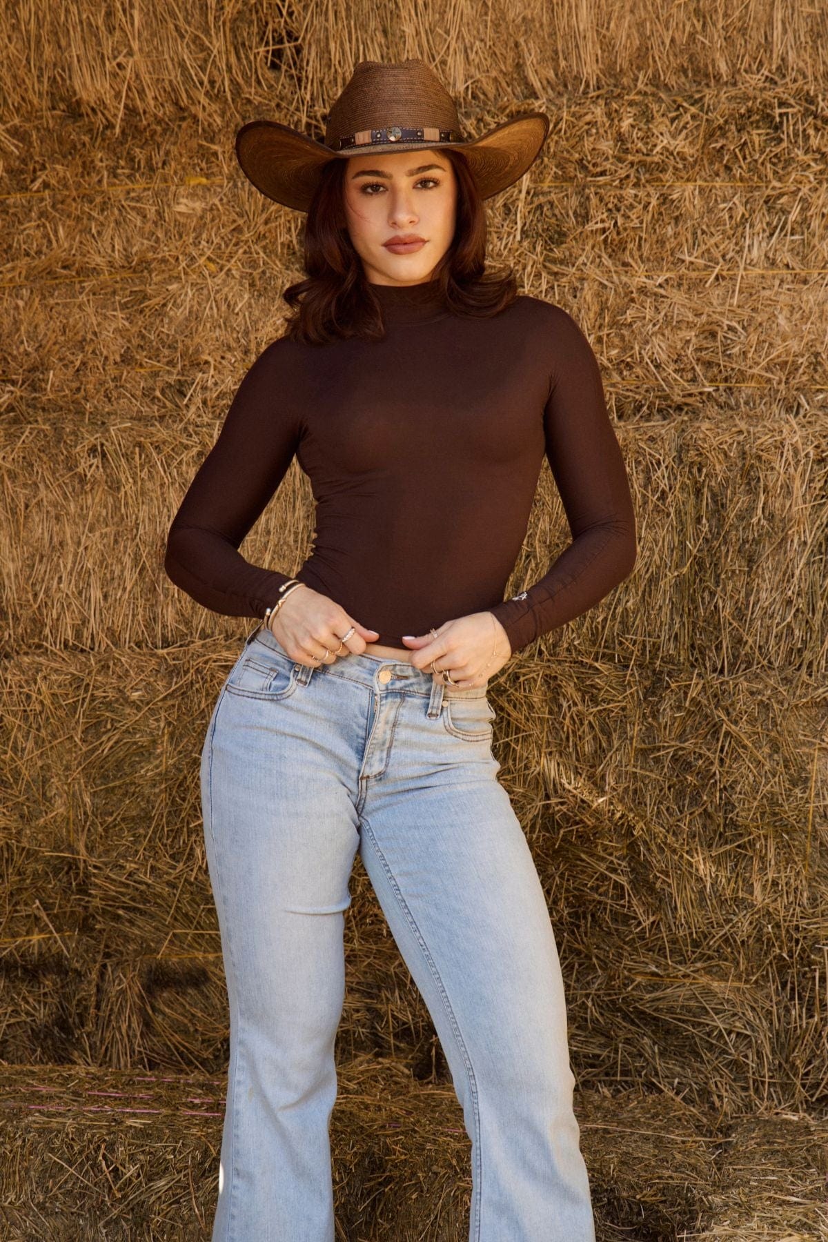 Model styling the fitted sheer long sleeve crop top with high-waisted jeans.